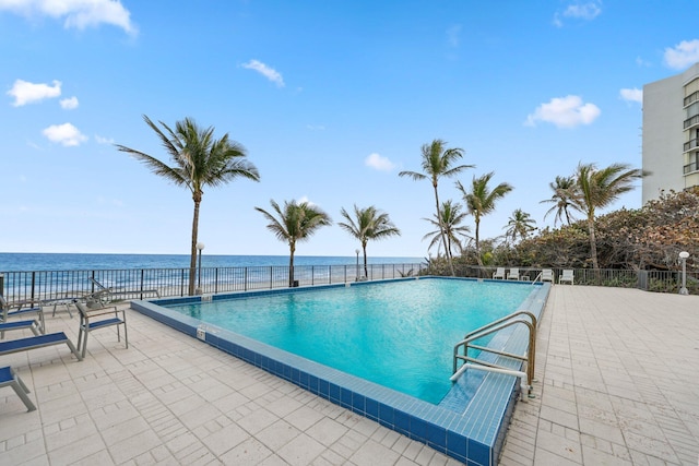 view of pool featuring a water view and a patio