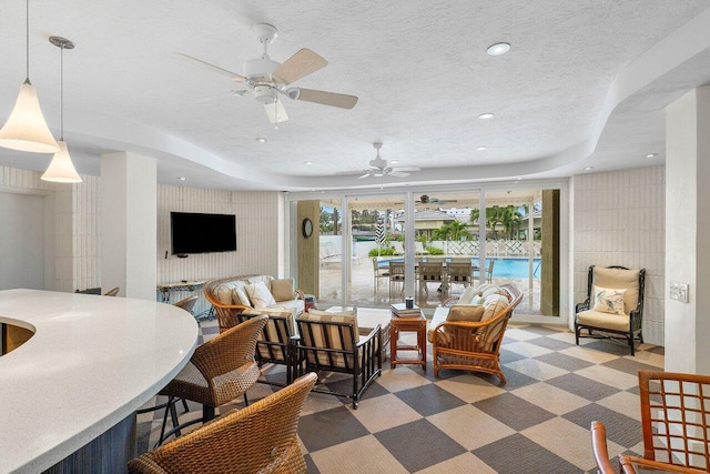 carpeted living room featuring a textured ceiling, a raised ceiling, and ceiling fan