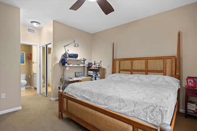 bedroom with a closet, ceiling fan, ensuite bathroom, and light colored carpet