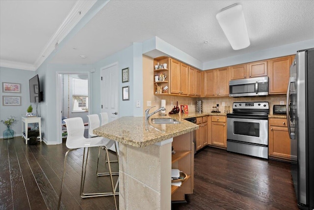 kitchen with kitchen peninsula, sink, a kitchen bar, dark hardwood / wood-style floors, and stainless steel appliances