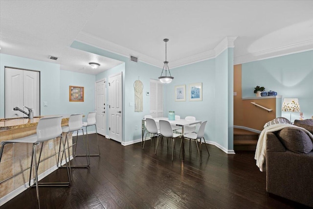 dining space with sink, ornamental molding, and dark hardwood / wood-style floors