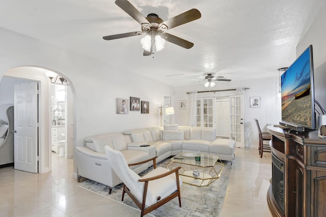 living room featuring a textured ceiling, ceiling fan, and light tile patterned flooring