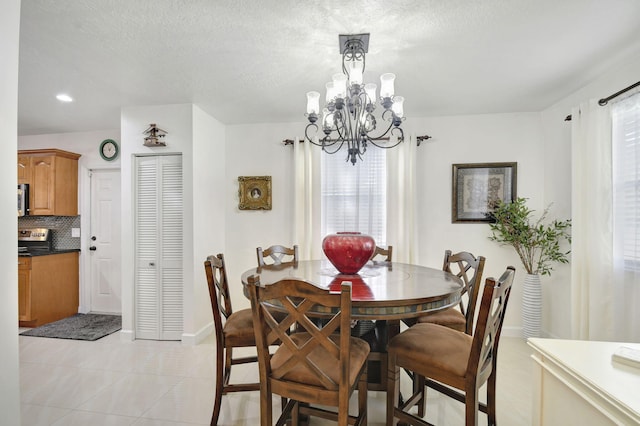 tiled dining space with a textured ceiling and a notable chandelier