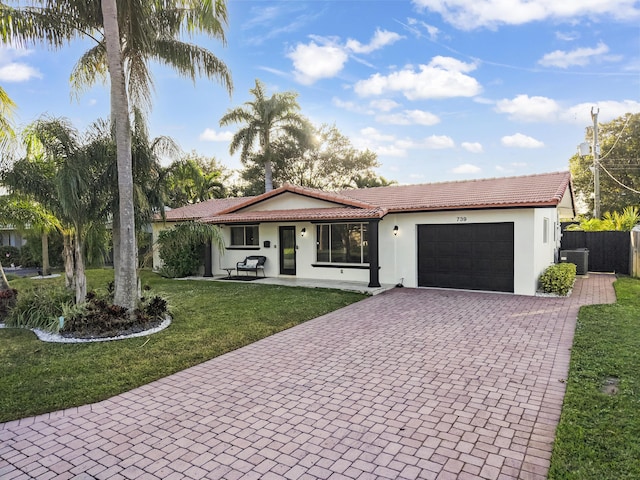 ranch-style home with a front yard, central AC unit, and a garage