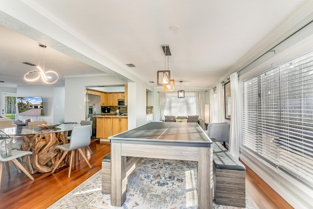 game room featuring hardwood / wood-style floors, a notable chandelier, and ornamental molding