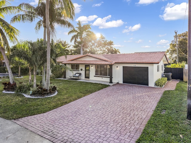 view of front of house with a front lawn, central AC unit, and a garage