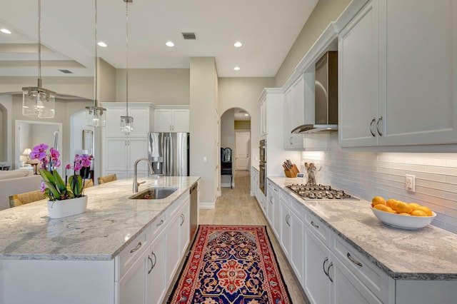 kitchen featuring appliances with stainless steel finishes, sink, white cabinets, hanging light fixtures, and a center island with sink