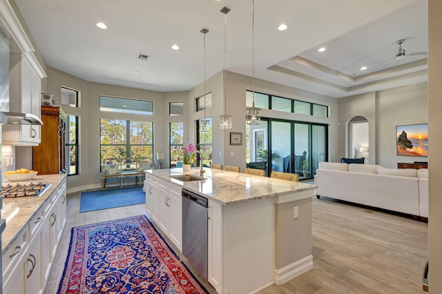 kitchen featuring sink, stainless steel appliances, light stone countertops, an island with sink, and white cabinets