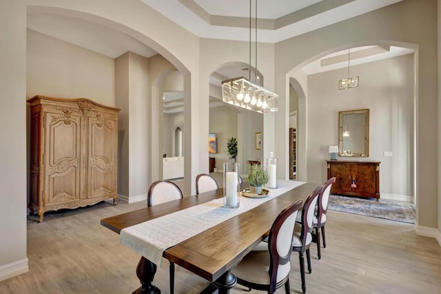 dining area with an inviting chandelier, a high ceiling, and light wood-type flooring