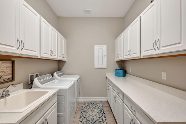 laundry area with cabinets, washing machine and dryer, sink, and electric panel