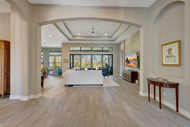 interior space with ceiling fan, a raised ceiling, light hardwood / wood-style flooring, and a towering ceiling