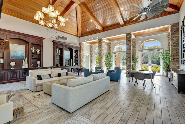 living room with a towering ceiling, ceiling fan with notable chandelier, wooden ceiling, and french doors