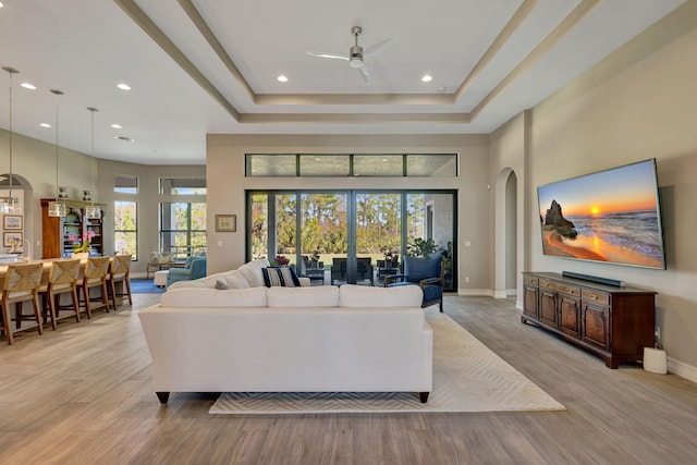 living room featuring ceiling fan, light wood-type flooring, and a high ceiling