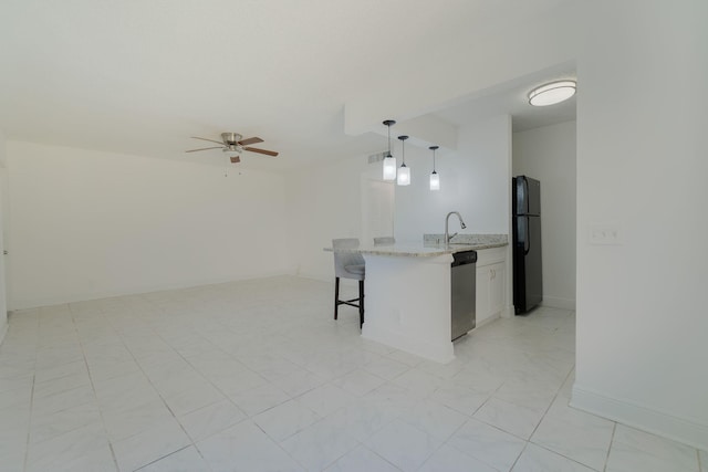 kitchen with pendant lighting, a breakfast bar, black refrigerator, white cabinetry, and stainless steel dishwasher