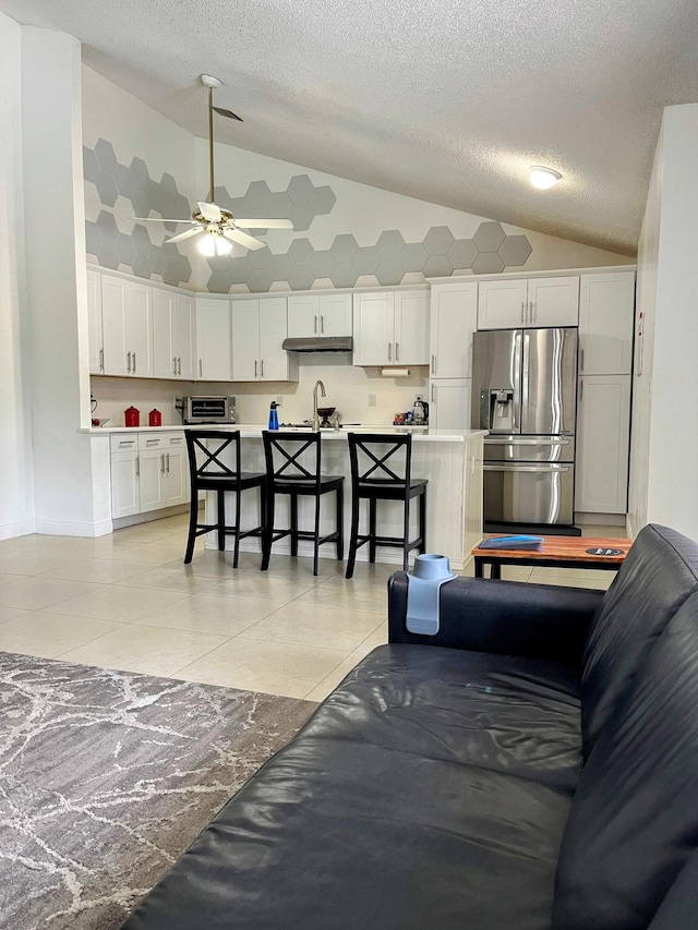 tiled living room featuring ceiling fan, vaulted ceiling, and sink