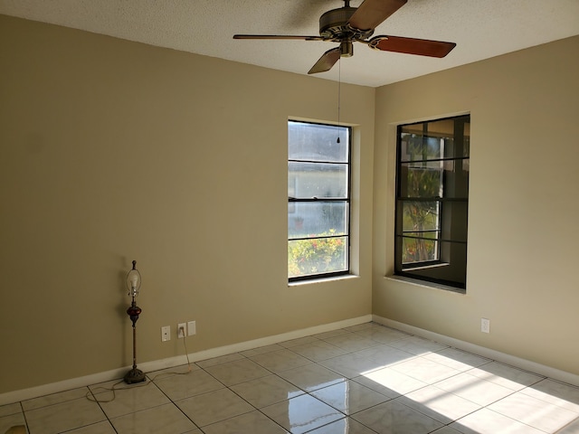 empty room with ceiling fan, a textured ceiling, and light tile patterned floors