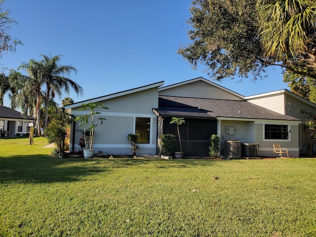 back of house featuring central AC unit and a lawn