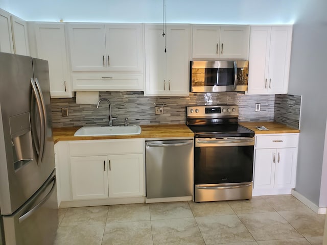 kitchen featuring wood counters, appliances with stainless steel finishes, white cabinets, and sink