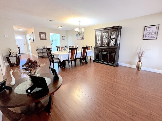 dining area featuring wood-type flooring and an inviting chandelier