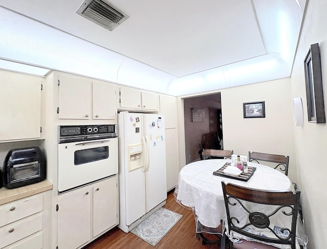 kitchen with white cabinets, dark hardwood / wood-style flooring, and white appliances