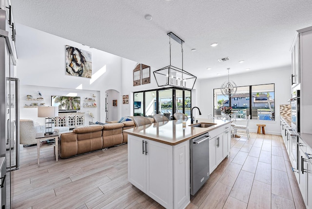 kitchen with sink, stainless steel appliances, white cabinetry, and a kitchen island with sink