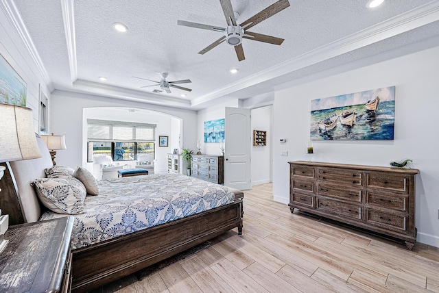 bedroom with a textured ceiling, ceiling fan, a tray ceiling, and crown molding