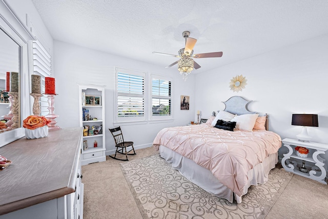 bedroom with ceiling fan, light carpet, and a textured ceiling