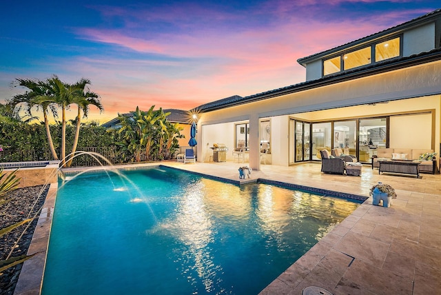 pool at dusk featuring pool water feature, a grill, outdoor lounge area, and a patio