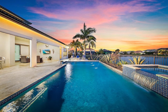 pool at dusk featuring a patio, pool water feature, cooling unit, and an in ground hot tub