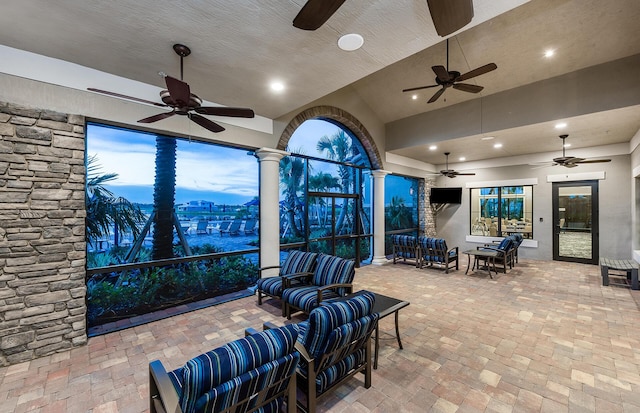 patio terrace at dusk featuring ceiling fan and an outdoor living space