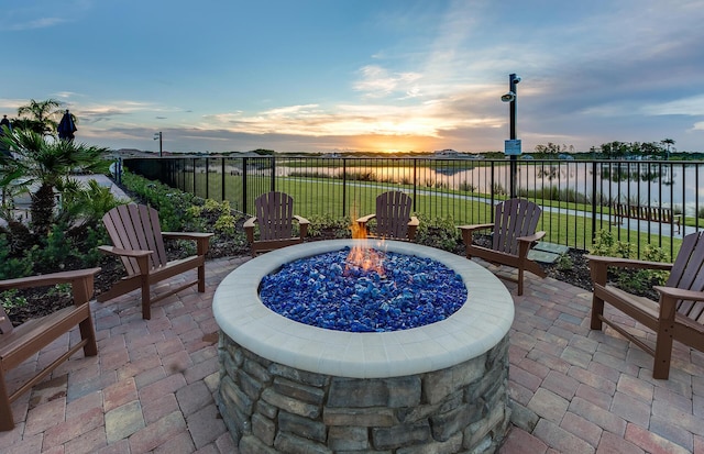 patio terrace at dusk with a fire pit and a water view