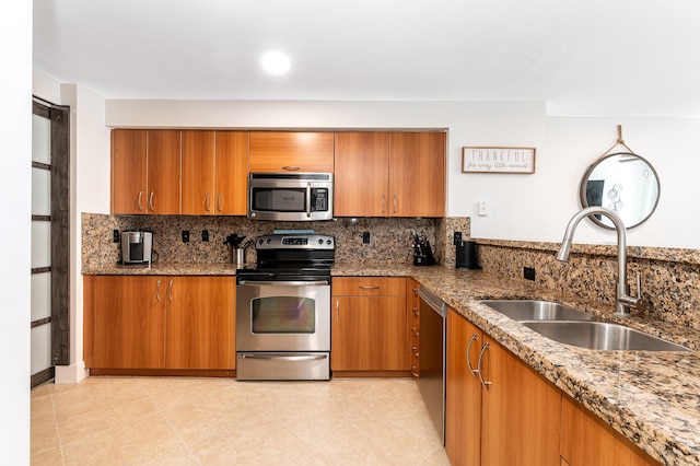 kitchen with stone counters, appliances with stainless steel finishes, decorative backsplash, and sink