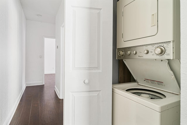 washroom featuring stacked washer and clothes dryer and dark hardwood / wood-style flooring