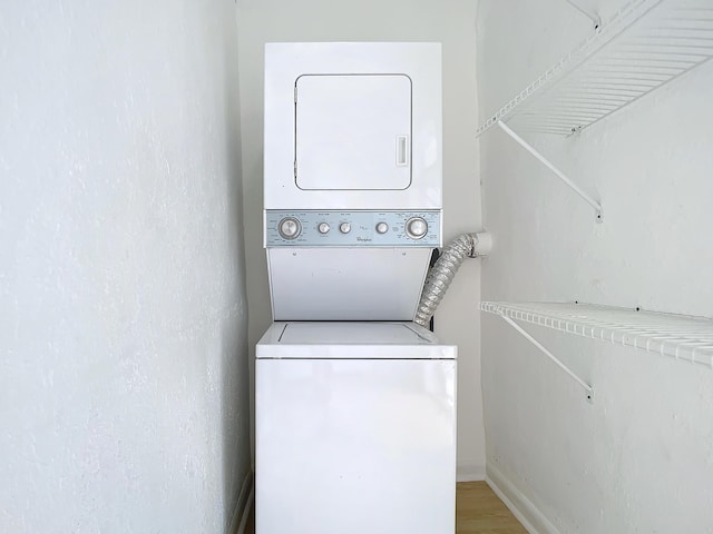 laundry area featuring stacked washer / drying machine and wood-type flooring