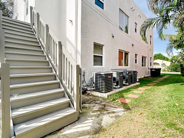 back of house with central AC and a lawn