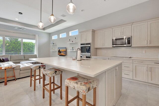 kitchen featuring tasteful backsplash, a breakfast bar, stainless steel appliances, a large island with sink, and hanging light fixtures