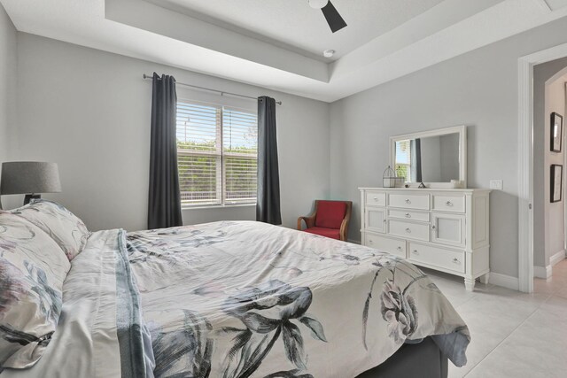 tiled bedroom with ceiling fan and a raised ceiling