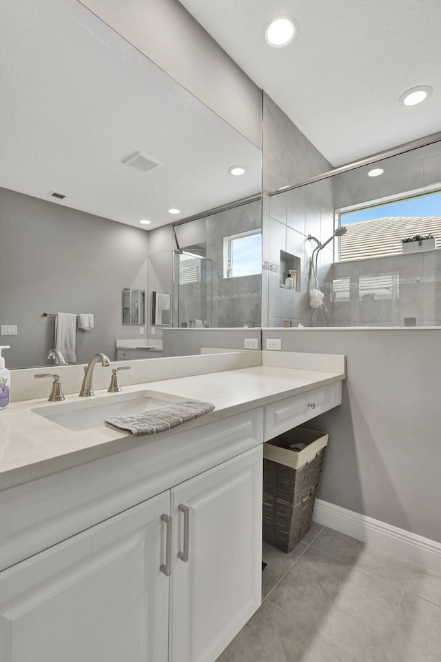 bathroom featuring tiled shower, vanity, and tile patterned flooring