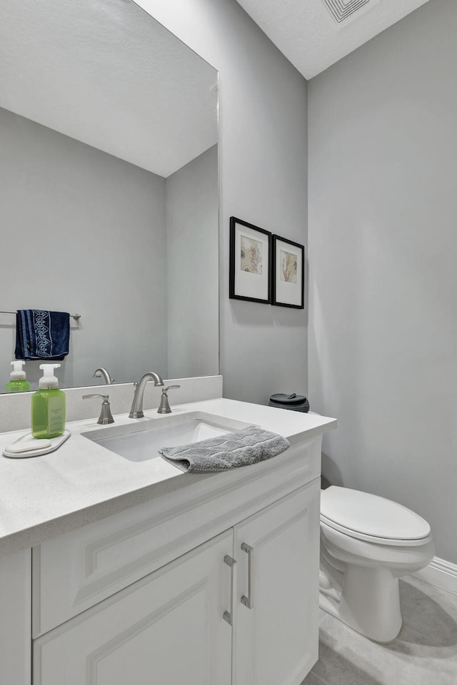 bathroom with toilet, vanity, and tile patterned flooring