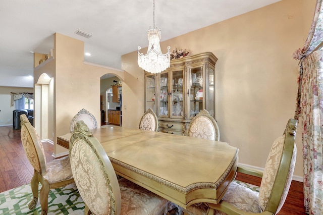 dining room with arched walkways, baseboards, wood finished floors, and a notable chandelier