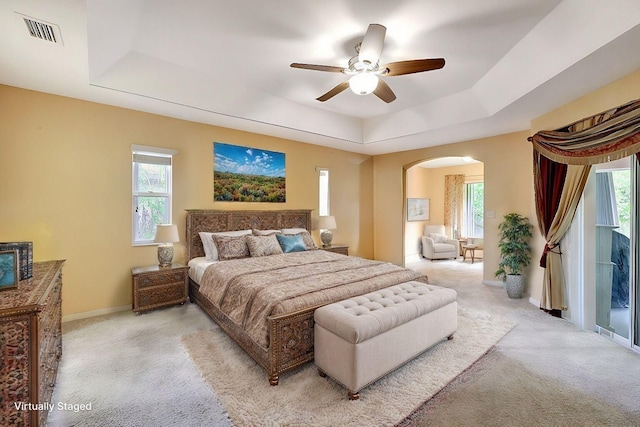 bedroom with multiple windows, visible vents, and a raised ceiling