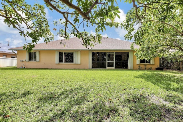 back of property with roof with shingles, stucco siding, a yard, and fence