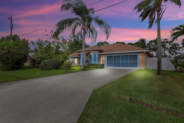 view of front facade featuring driveway, fence, a lawn, and stucco siding