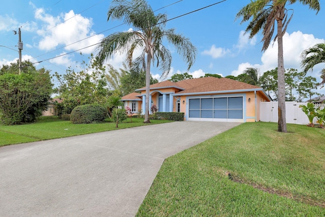 view of front of property with concrete driveway, a front lawn, fence, and stucco siding