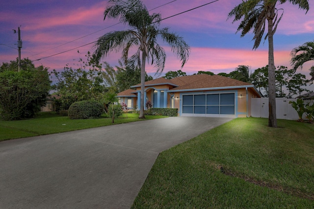 ranch-style house featuring an attached garage, fence, a front lawn, and concrete driveway