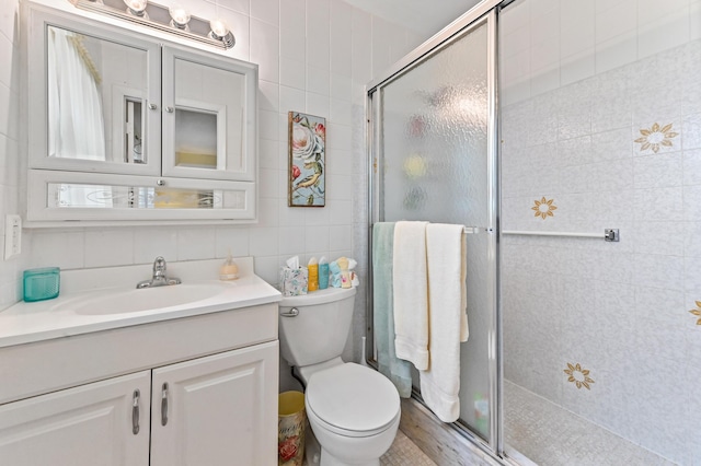 bathroom featuring tile walls, vanity, an enclosed shower, and toilet