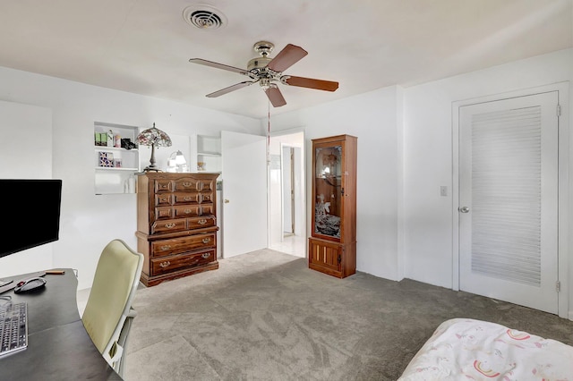 office area featuring built in shelves, light carpet, and ceiling fan