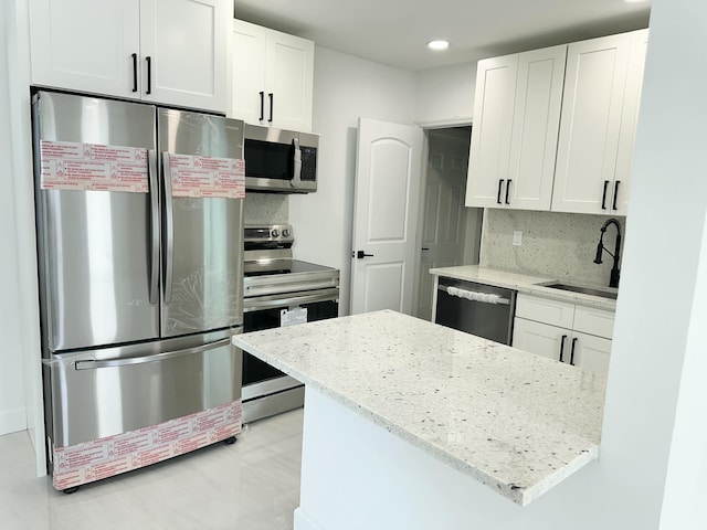 kitchen with white cabinets, light stone countertops, sink, and stainless steel appliances