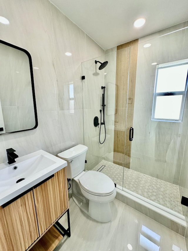 bathroom with a shower with door, tile walls, toilet, and vanity