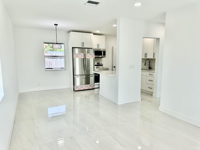 kitchen featuring white cabinets, appliances with stainless steel finishes, decorative light fixtures, decorative backsplash, and sink